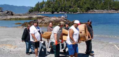 Des membres de la Première nation Tseshaht et du personnel de la sécurité publique de la réserve de parc national du Canada Pacific Rim transportent le poteau de maison, du bateau vers sa destination finale
