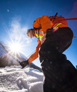 Un employé de Parcs Canada habillé en équipement de sécurité fait le profilage de la neige