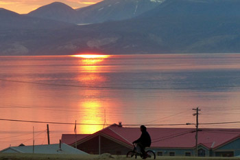 Garçon sur un vélo avec un village et un paysage arctiques en arrière-plan