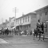 Photo en noir et blanc de gens dans une rue et un homme sur un cheval
