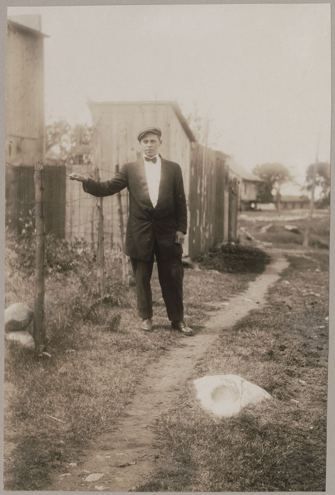 Photo historique d'une homme debout près d'une cloture