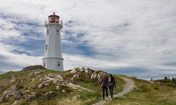Deux personnes marchant sur un chemin près d'un phare.