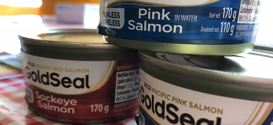 Trois boîtes de saumon de supermarché moderne empilées les unes sur les autres.