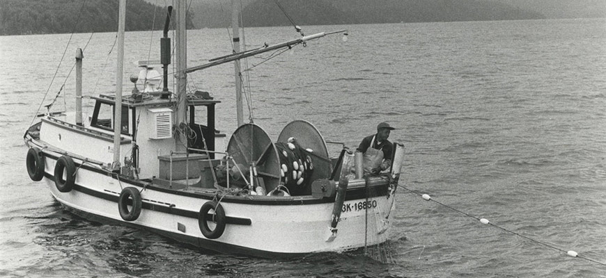 Plan fixe tiré d’un film d’époque noir et blanc ayant pour personnage principal une personne pêchant depuis un bateau avec des îles en arrière-plan