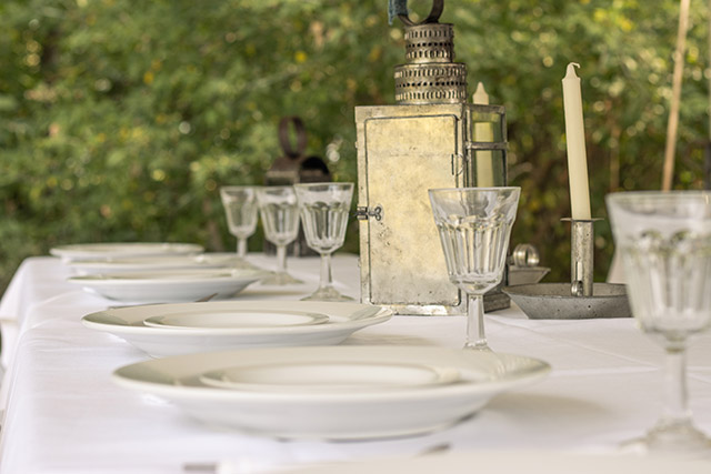 Des assiettes, des verres et des décorations sont posés sur une table sous une tente au lieu historique national de la Maison-Riel.