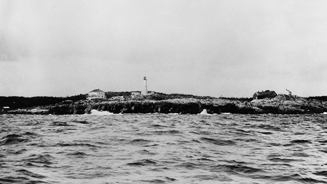 Photo prise de la mer, vue du phare de Louisbourg, de la maison du gardien du phare, et de la maison de son assistant.
