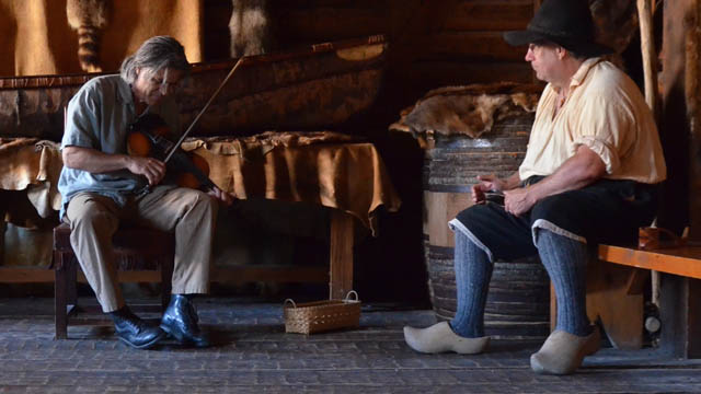 Un homme avec un violon et un homme portant des sabots en bois.