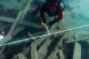 Le plongeur pose un quadrant de lignes blanches au-dessus des débris dispersés sur le fond de l'océan.