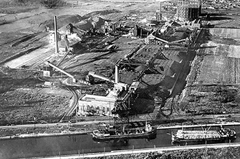 Photo d'archive en vue aérienne d'une usine qui transforme le charbon avec un convoyeur du canal de Lachine jusqu'à l'usine.