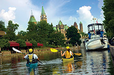 Kayakiste dans le Canal Rigaud avec la ville d'Ottawa en arrière plan.