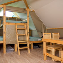 À l'intérieur d'un hébergement oTENTik, on retrouve un espace pour dormir séparé par des rideaux, une table et des chaises de cuisine ainsi qu'un comptoir pour préparer les repas et ranger le matériel.