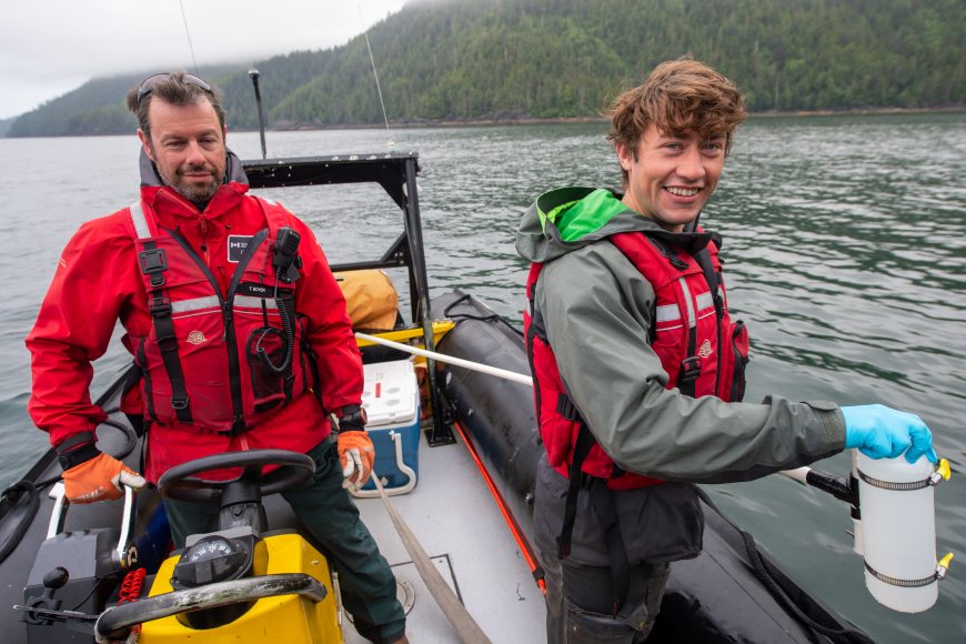Deux chercheurs travaillent sur un bateau sur l’eau dans le cadre de la collecte d’un échantillon d’eau.