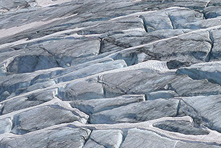 Vue aérienne d’un glacier avec des crevasses et des zones de neige.