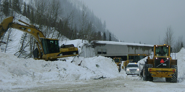 Des ouvriers de la voirie de Parcs Canada dégagent les débris d’avalanche de la route. 