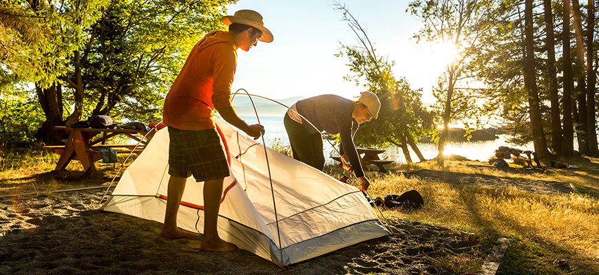 Deux campeurs montent leur tente au soleil couchant au camping de la baie Shingle sur l'Île Pender