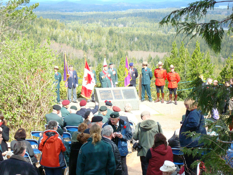 Des officiers se tiennent sur la colline Radar près du monument commémoratif, entourés de drapeaux et de spectateurs