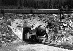 La locomotive d'un train à vapeur croise le wagon de queue à sa sortie du tunnel inférieur.