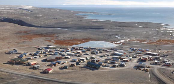 Vue du sommet d’une colline surplombant un petit village de l’Arctique, au bord de l’océan.
