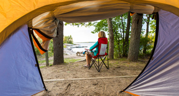 Quelqu'un est assis sur une chaise de camping devant une tente.