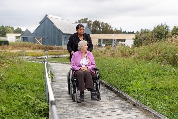 Deux femmes dont l’une en fauteuil roulant circulent sur un pavé en bois