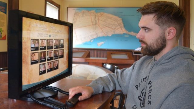 Un homme regarde un écran interactif dans une exposition.