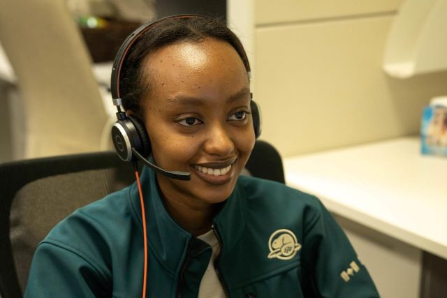Une employée étudiante d'ascendance africaine parle dans un casque d'écoute. 
