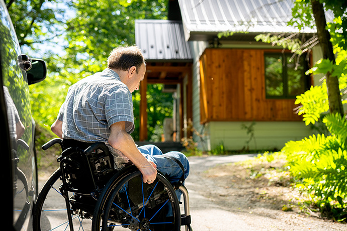 Un visiteur en fauteuil roulant sort de sa camionette devant le chalet.