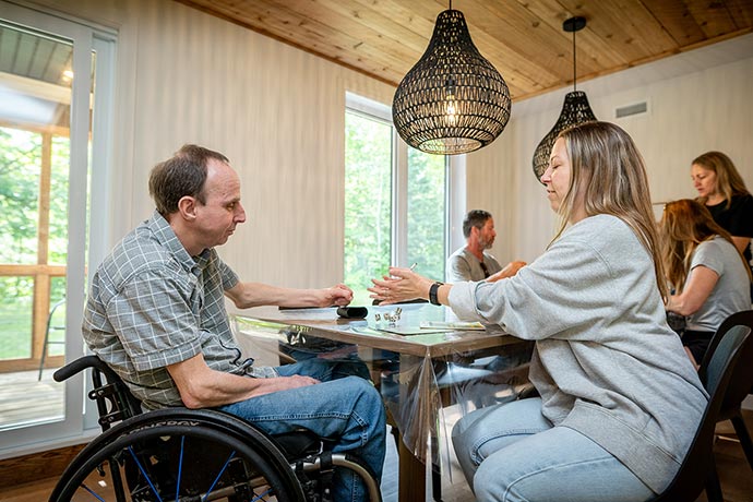 Des visiteurs jouent à des jeux de société sur la grande table de la salle à dîner.