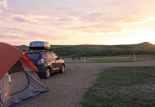 Une voiture dans un camping au coucher du soleil.