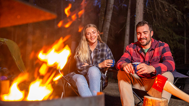 Un groupe d’amis composé de jeunes adultes passe du temps ensemble auteur d’un feu de camp à son emplacement de camping sur le terrain de camping Beaver Glen, pendant l’été, au parc national de Prince Albert. 