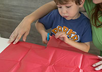 Jeune garçon coupe papier de soie.