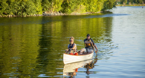 Deux visiteurs et un chien font du canot au lieu historique national du Canal-Rideau.