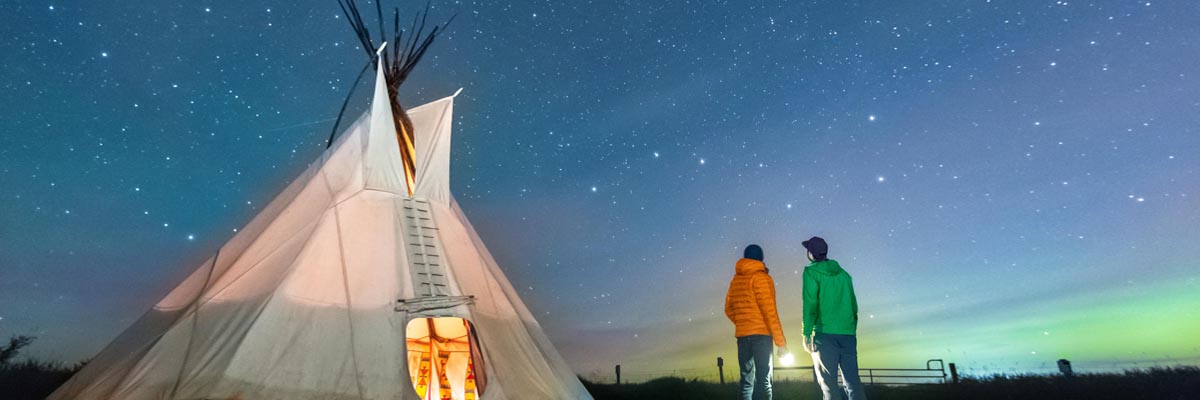 Deux visiteurs contemplent la Grande Ourse lors d'une nuit étoilée au lieu historique national Rocky Mountain House.