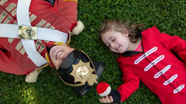 Une jeune fille costumée en soldat et un soldat sont couchés dans l’herbe au lieu historique national du Fort-Malden.