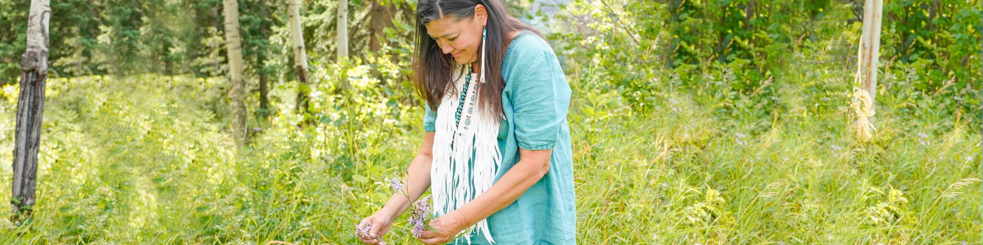 Une femme autochtone cueille des plantes dans la forêt du parc national Jasper.