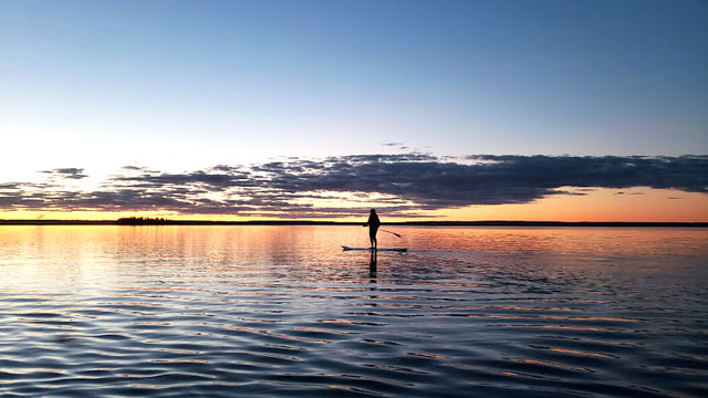 Un visiteur sur une planche à pagaie sur le lac Waskesiu près de l’île King lors du coucher du soleil au parc national de Prince Albert.