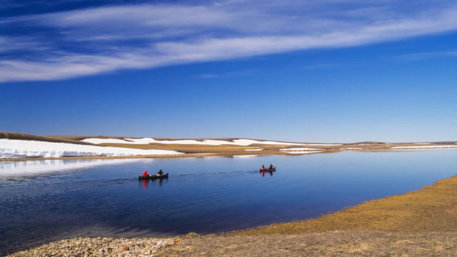 Deux canots sur la rivière Thomsen à Aulavik avec de la neige et la toundra en arrière-plan.