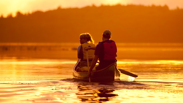 Deux adultes en canot lors d’un coucher de soleil orangé à Kejimkujik.