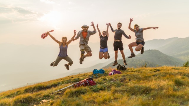 Cinq jeunes adultes sautent pour une photo au sommet de la colline Opal dans le parc national Jasper.