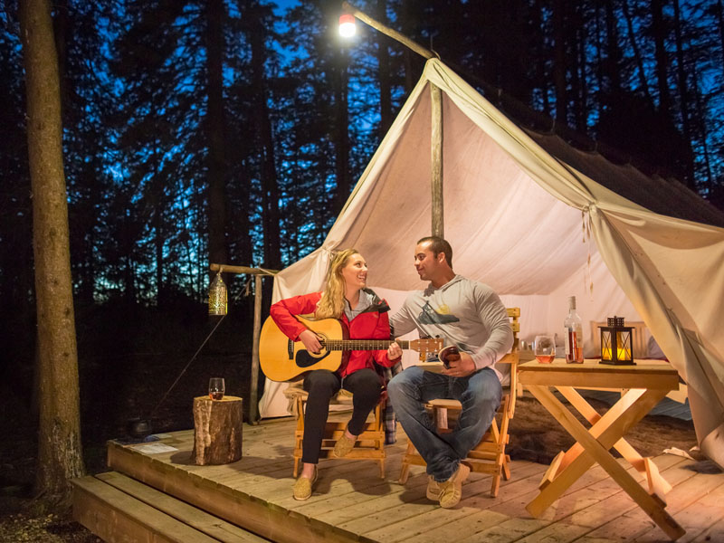 Un couple est assis devant une tente de trappeur métis tout équipée.