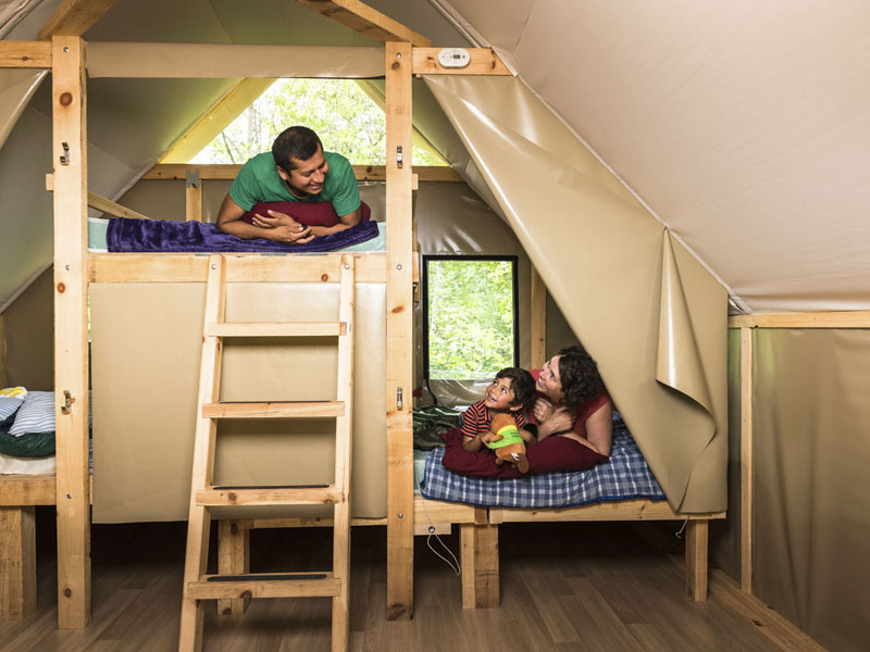 Une famille profite de son séjour dans une tente oTENTik. Les gens sont étendus sur les lits.