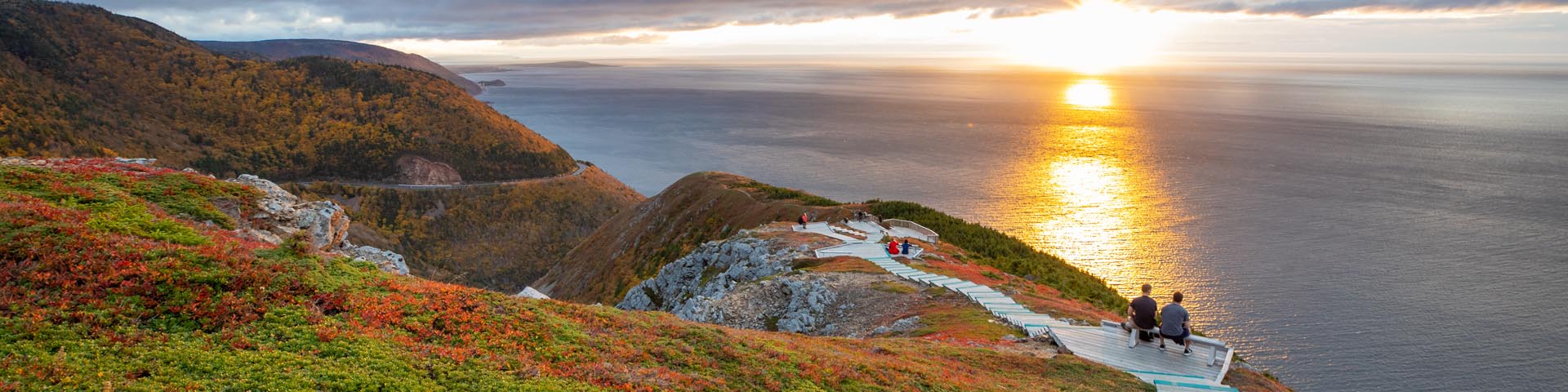 Des visiteurs sur les belvédères du sentier Skyline lors d’un coucher de soleil au parc national des Hautes-Terres-du-Cap-Breton.