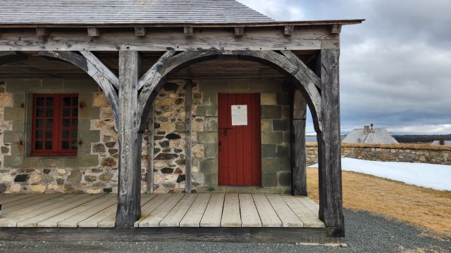 La devanture du corps de garde, montrant particulièrement l’arche de la galerie et la porte rouge. 