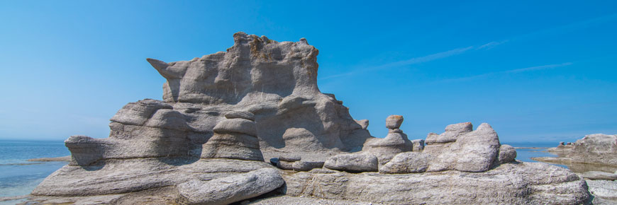 Des monolithes qui ressemblent à un château sur une plage de galets
