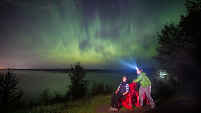 Un couple sur des chaises rouges observe les aurores boréales.