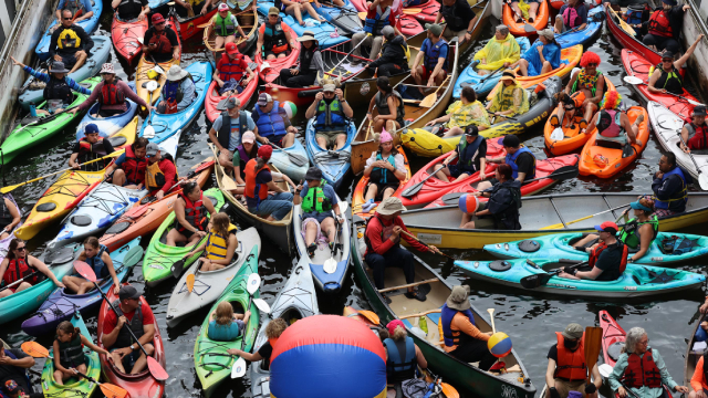 Des kayakistes dans des kayaks de toutes les couleurs sont entassés dans une écluse historique.